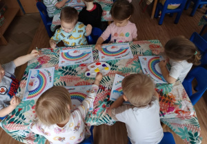 Dzieci malują tęczę patyczkami zamoczonymi w farbie
