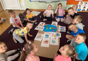 Dzieci siedzą w kole przy ilustracjach o ochronie środowiska