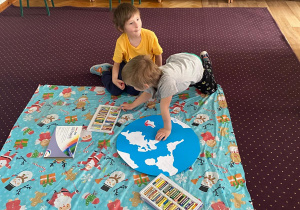 Dzieci oglądają wyciętą z papieru planetę Ziemię