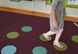 Dziewczynka chodzi po kolorowych krążkach.