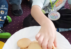Chłopiec częstuje się ciastkiem w kształcie kropki.
