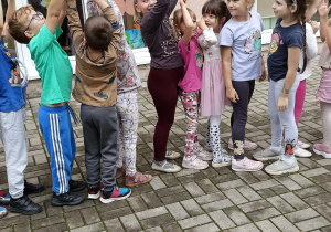 Dzieci stoją w rzędzie i podają sobie górą woreczek