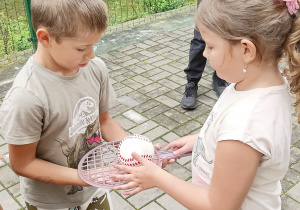 Chłopiec podaje rakietkę z piłką do dziewczynki