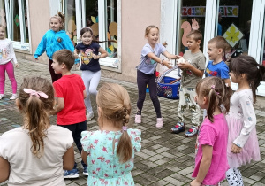 Dzieci stoją w kole i podają sobie piłkę