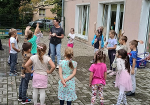Dzieci stoją w kole i podają sobie piłkę