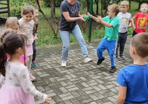 Dzieci stoją w kole i podają sobie piłkę