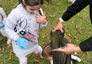 Dziewczynka wrzuca śmieci do worka