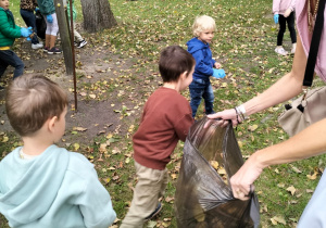 Chłopiec wrzuca śmieci do worka