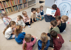 Dzieci słuchają opowiadania czytanego przez panią bibliotekarkę