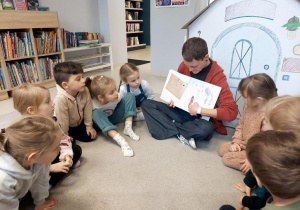 Dzieci słuchają opowiadania czytanego przez panią bibliotekarkę