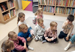 Dzieci słuchają opowiadania czytanego przez panią bibliotekarkę
