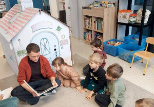 Dzieci słuchają opowiadania czytanego przez panią bibliotekarkę