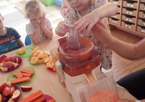 Dzieci wkładają owoce i warzywa do wyciskarki