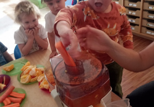 Dzieci wkładają owoce i warzywa do wyciskarki