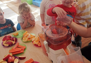 Dzieci wkładają owoce i warzywa do wyciskarki