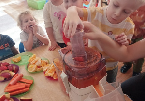 Dzieci wkładają owoce i warzywa do wyciskarki