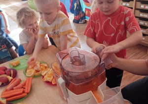 Dzieci wkładają owoce i warzywa do wyciskarki