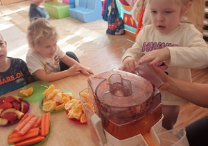 Dzieci wkładają owoce i warzywa do wyciskarki