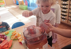 Dzieci wkładają owoce i warzywa do wyciskarki