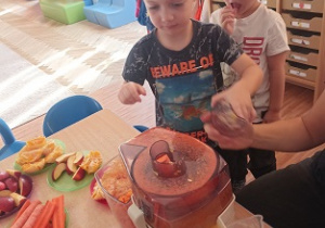 Dzieci wkładają owoce i warzywa do wyciskarki