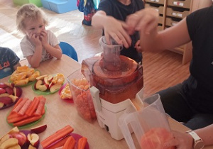 Dzieci wkładają owoce i warzywa do wyciskarki