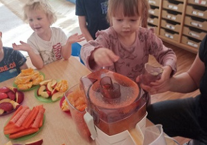 Dzieci wkładają owoce i warzywa do wyciskarki