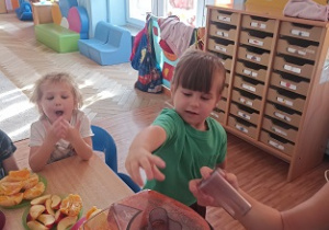 Dzieci wkładają owoce i warzywa do wyciskarki