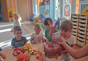 Dzieci wkładają owoce i warzywa do wyciskarki