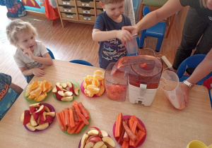 Dzieci wkładają owoce i warzywa do wyciskarki