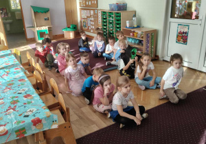 Dzieci siedzą w dwóch rzędach i czekają na swoją kolej, żeby wykonać zadania.