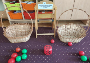 Dwa puste kosze, piłeczki i kostka do gry.