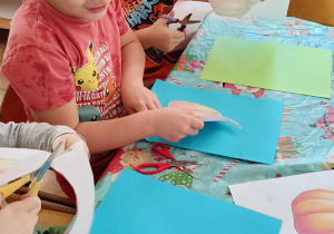 Dzieci wykonują pracę plastyczną - ozdabiają papierowe dynie.