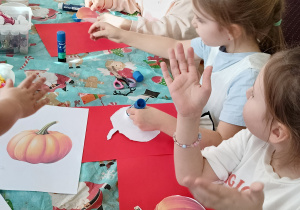 Dzieci wykonują pracę plastyczną - ozdabiają papierowe dynie.