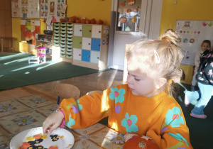 Dziewczynka z grupy II ozdabia dynię