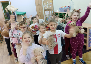 Dzieci machają ręką trzymając swojego pluszowego misia