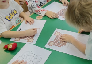 Dzieci kolorują obrazek z misiem