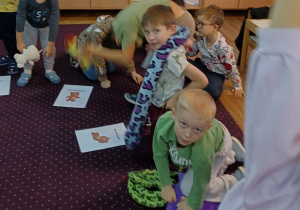 Dzieci wykonują skłony w przód z misiem