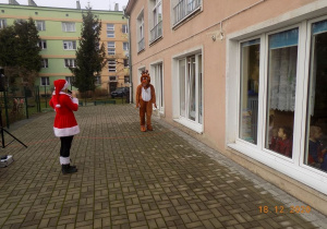 Asystentka Mikołaja zaprasza dzieci do wspólnych zabaw mikołajkowych