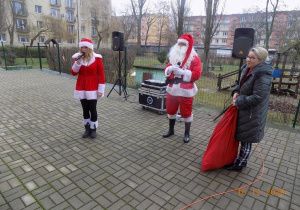 Mikołaj i jego asystentka przekazują Dyrektor przedszkola worek z prezentami