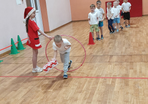 Chłopiec przechodzi przez koło hula-hop z paczką prezentową.