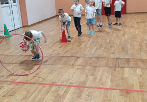 Chłopiec przechodzi przez koło hula-hop z paczką prezentową.