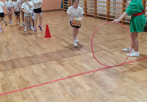 Dziewczynka biegnie w stronę koła hula-hop.