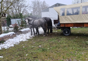 Dzieci siedzą w wozie zaprzęgniętym w konie. Szykują się do przejażdżki.