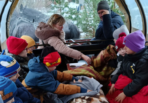 Dzieci siedzą w wozie zaprzęgniętym w konie. Szykują się do przejażdżki.