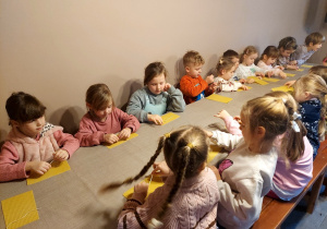 Dzieci wykonują świecę z plastra wosku.