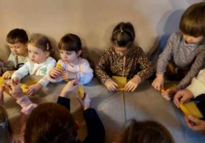 Dzieci wykonują świecę z plastra wosku.