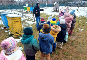 Przewodnik oprowadza dzieci po pasiece.
