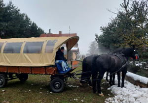 Wóz zaprzęgnięty w konie czeka na przewóz dzieci.