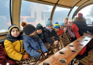 Dzieci jadą wozem zaprzęgniętym w konie.