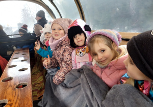 Dzieci jadą wozem zaprzęgniętym w konie.